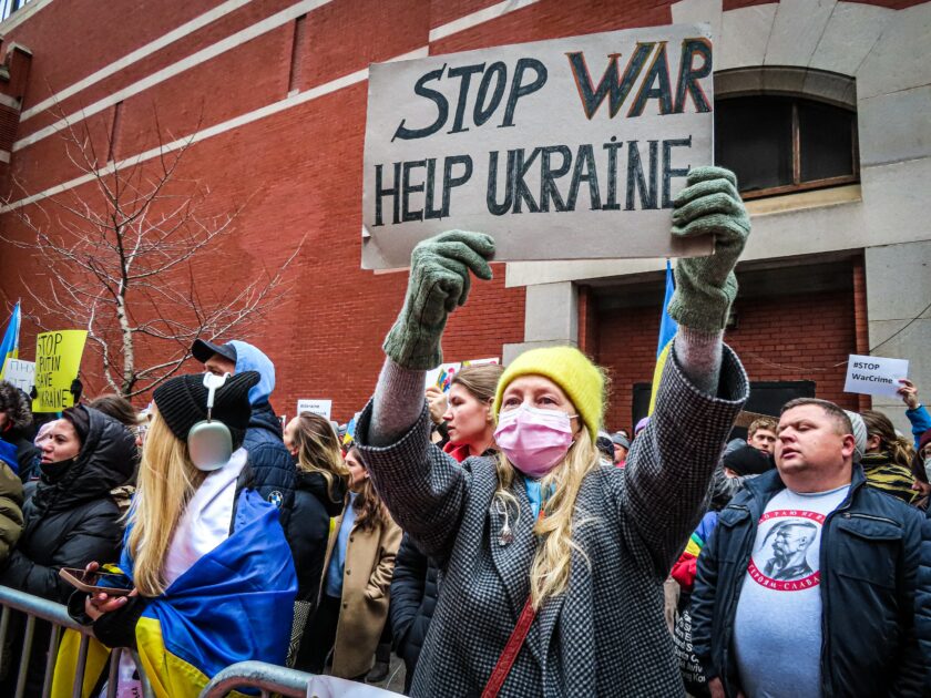 Ukrainalaisia osoittamassa mieltään. Nainen pitää kylttiä, jossa lukee Stop was, Help ukarainians.