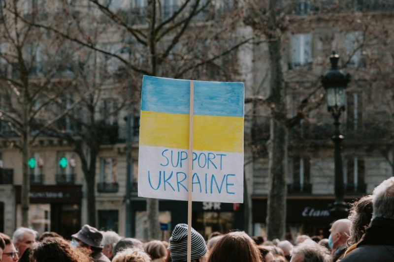 Mielenosoitus. Kuvassa näkyy päälakia, joiden yläpuolelle nostettu yksi sini-keltainen kyltti, jossa lukee support ukraine.